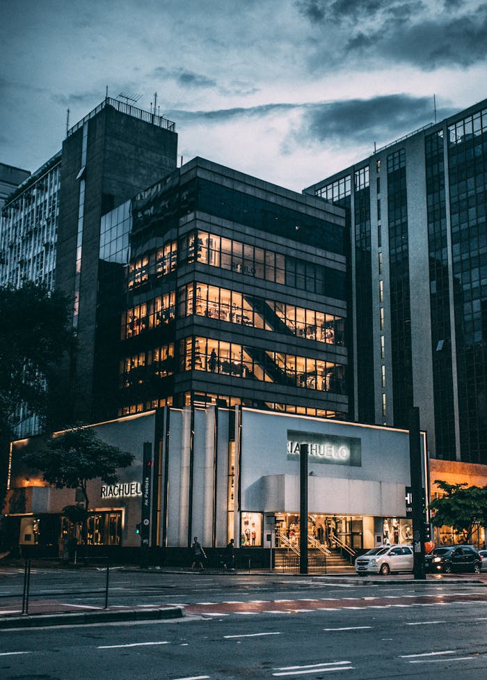 pexels-photo-65438 Night view of a city block with illuminated store, modern architecture, and cloudy sky.