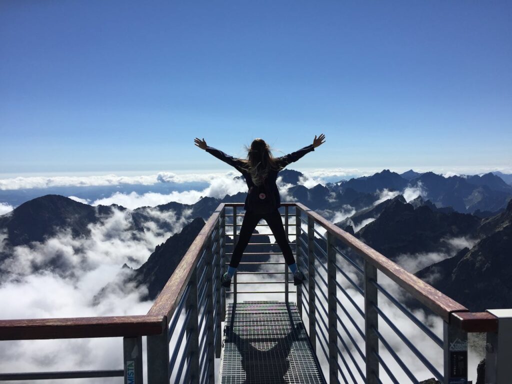 pexels-photo-725255 A woman stands on a viewing platform in Vysoké Tatry, Slovakia, surrounded by clouds and mountains, embracing freedom.